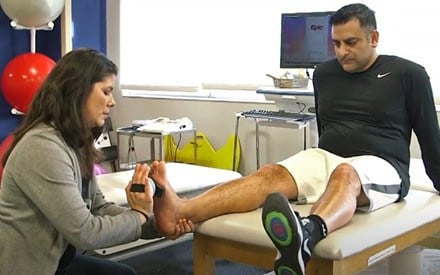 Physical therapist providing hands-on therapy for a man with an achilles injury.