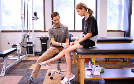 A teen with a physical therapist for treatment of knee pain.