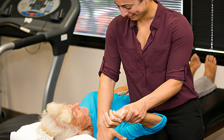 A physical therapist using manual therapy to mobilize an older adult's shoulder.
