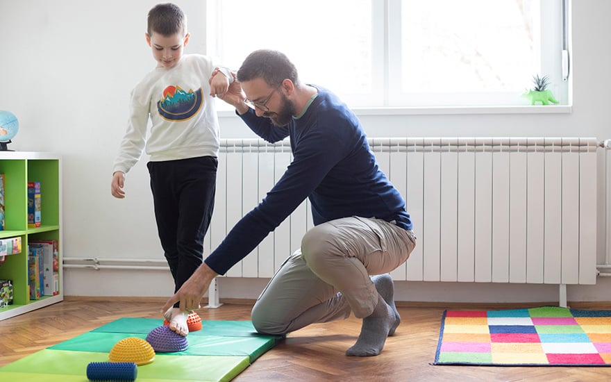 A physical therapist works with a child on exercises to improve flat feet.