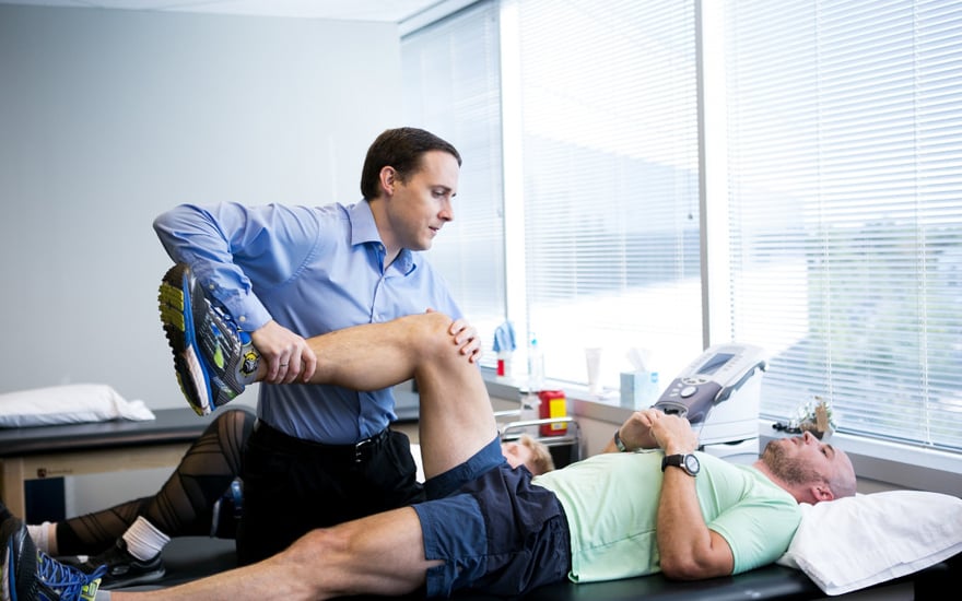 A physical therapist works on a patient's leg .