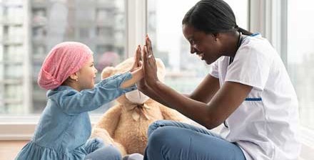 An oncologic physical therapist gives a high five to a young cancer patient.