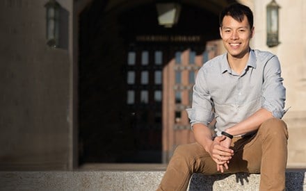 Jonathan, sitting on the steps of a college building.