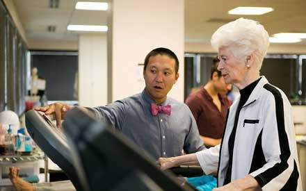 A physical therapist working with an older adult on a treadmill.