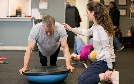 A physical therapist working with a patient on strengthening exercises