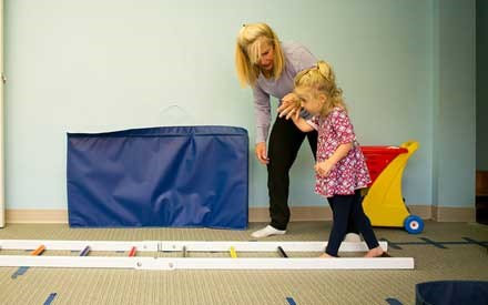 A pediatric physical therapist working with a young child on walking skills.