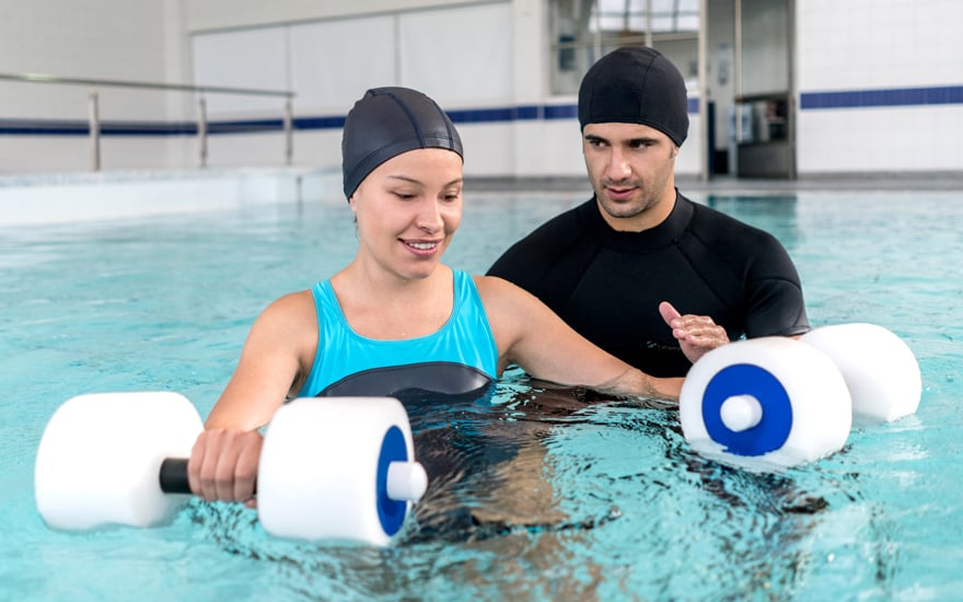 A physical therapist teaches a patient an aquatic exercise program.