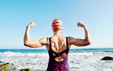 Swimmer flexing arm muscles in front of ocean