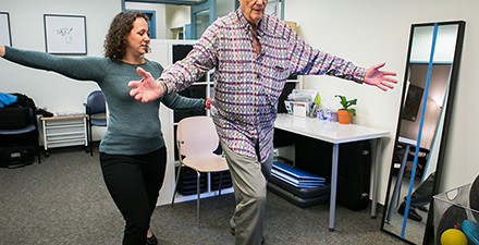 A physical therapist is working with a patient on large movement activities.